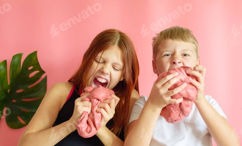 Preview: Cute Blonde Boy And Red Hair Girl Playing With Hand Made Slime On Pink Background