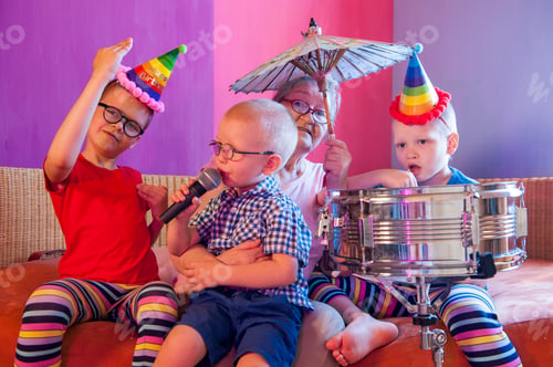 Preview: Elderly Woman In Pink T-Shirt And Glasses Holding Megaphone. Next To Grandmother, Grandchildren In