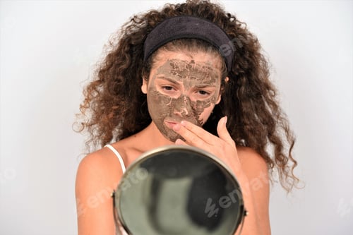 Preview: Young Woman with Facial Mask Looks in Mirror