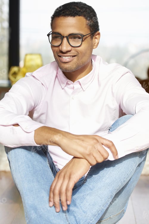 Preview: Portrait Of A Young Casual Man Sitting At Home And Looking Thoughtfully Away.