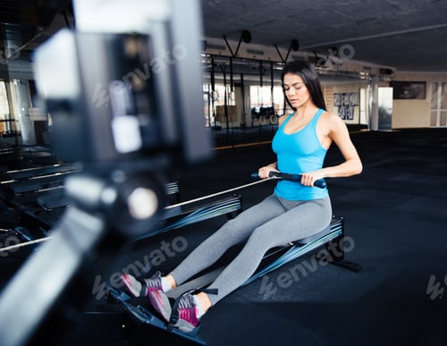 Preview: Portrait Of A Cute Woman Doing Exercise On Simulator At Gym