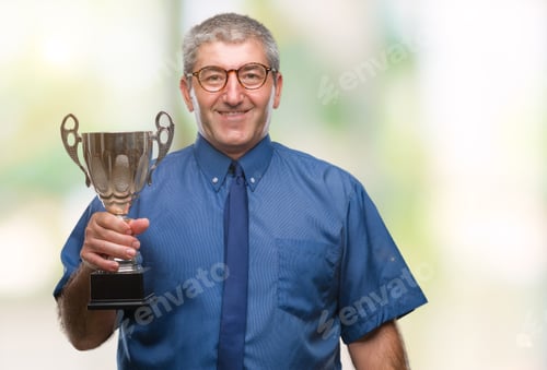 Preview: Handsome Senior Successful Man Holding Trophy Over Isolated Background With A Happy Face Standing