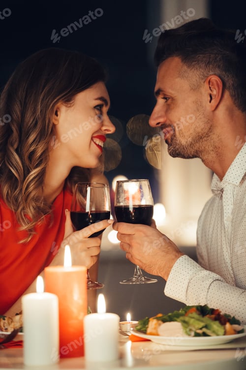 Preview: Young Smiling Beautiful Lovers Looking At Each Other And Have Romantic Dinner With Wine And Food