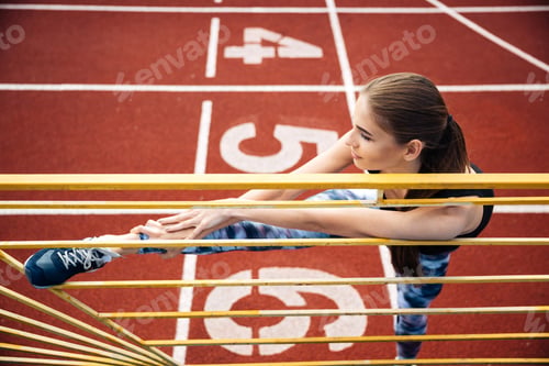 Preview: Portrait Of A Beautiful Sports Woman Stretching Legs On Outdoor Stadium