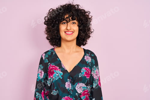 Preview: Young Arab Woman With Curly Hair Wearing Floral Dress Over Isolated Pink Background With A Happy