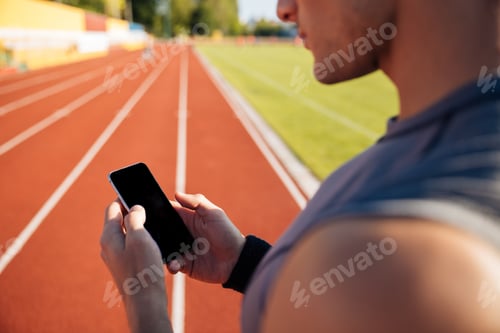 Preview: Cropped Image Of A Handsome Man Resting After Run And Using Smartphone On Outdoor Stadium