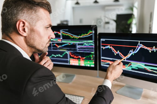 Preview: Photo Of European Businessman 30S Wearing Suit Sitting At Table In Office And Working With Graphics