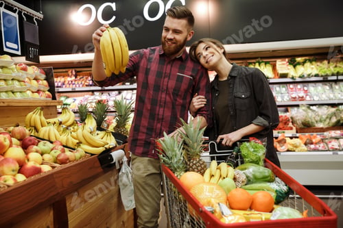 Preview: Photo Of Happy Young Loving Couple In Supermarket With Shopping Trolley Choosing Fruits. Looking
