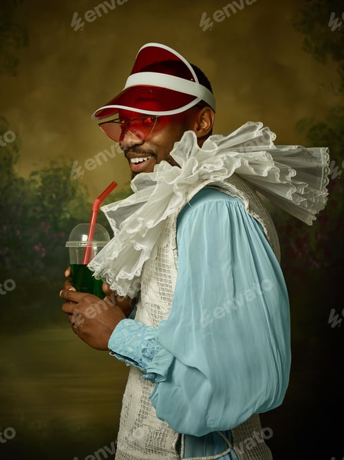 Preview: Young Man As A Medieval Grandee Or Nobleman On Dark Studio Background. Male Model In A Cap And