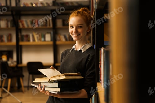 Preview: Smiling Red Haired Teenage Girl Carrying Books At The Library