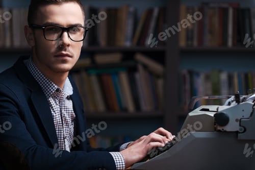 Preview: Confident Young Author. Side View Of Confident Young Author Sitting At The Typewriter And Looking
