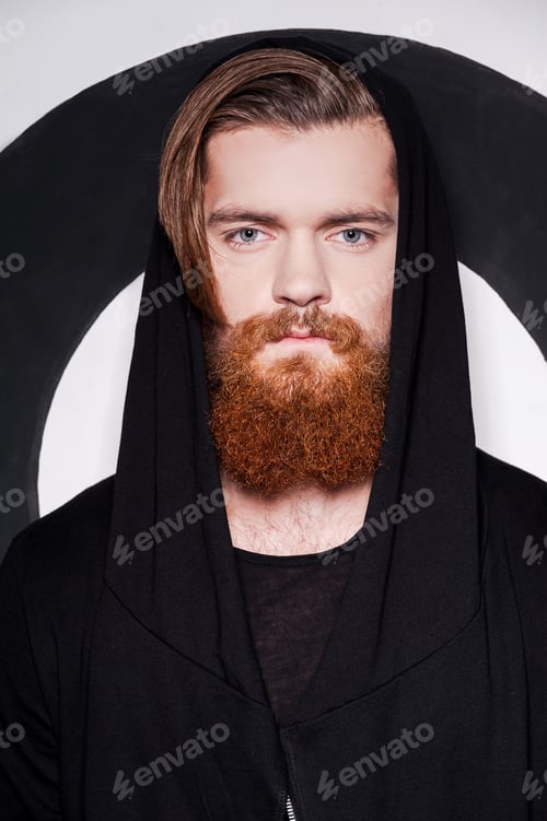 Preview: Beauty And Style. Handsome Young Bearded Man Wearing Hood And Looking At Camera While Standing