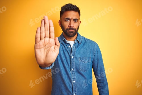 Preview: Young Indian Man Wearing Denim Shirt Standing Over Isolated Yellow Background Doing Stop Sing With