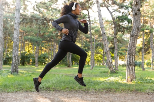 Preview: Image Of Feminine Woman 20S Wearing Black Tracksuit And Headphones Working Out While Running