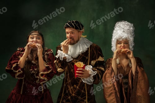 Preview: Taste Of Future. Portrait Of Medieval Young People In Vintage Clothing On Dark Background. Models