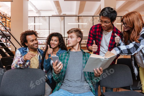 Preview: Boy With Smartphone And Book Sitting With His Friends Showing Thumbs Up