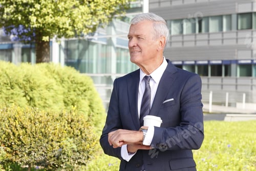 Preview: Portrait Of Senior Manager Standing At Office Building And Checking The Time On Watch While Waiting