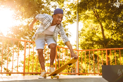 Preview: Happy Young African Man With Skateboard Riding On A Ramp At The Skate Park