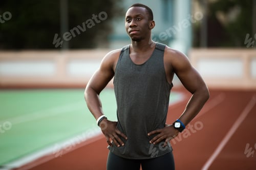 Preview: Young Male Athlete Standing At The Stadium Race Track With Hands On Hips