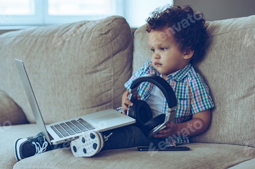 Preview: Technologies Make Life Easier. Side View Of Little African Baby Boy Looking At Laptop And Holding