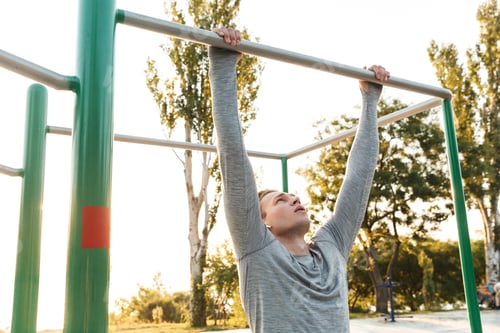 Preview: Concentrated Young Sportsman Doing Exercises On Bars Outdoors
