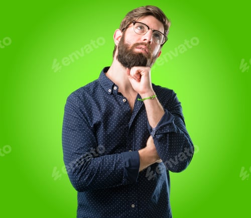 Preview: Young Hipster Man With Big Beard Thinking And Looking Up Expressing Doubt And Wonder Over Green