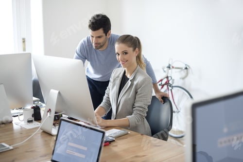 Preview: Shot Of A Happy Young Businesswoman Sitting In Front Of Computer While Her Handsome Colleague