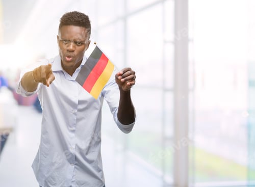 Preview: Young African American Man Holding German Flag Pointing With Finger To The Camera And To You, Hand