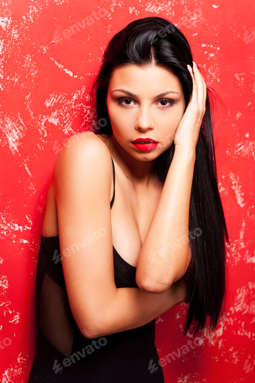 Preview: Gorgeous Beauty On Red. Beautiful Young Woman Posing And Looking At Camera While Standing Against