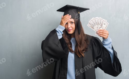 Preview: Young Brunette Woman Over Grunge Grey Wall Wearing Graduate Uniform Holding Dollars Stressed With