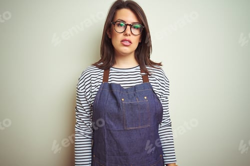 Preview: Young Beautiful Business Woman Wearing Store Uniform Apron Over Isolated Background With Serious