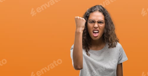 Preview: Beautiful Young Hispanic Woman Wearing Glasses Angry And Mad Raising Fist Frustrated And Furious