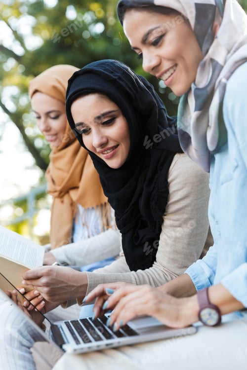 Preview: Photo Of Attractive Muslim Girls Wearing Headscarfs Resting In Green Park And Studying On Laptop