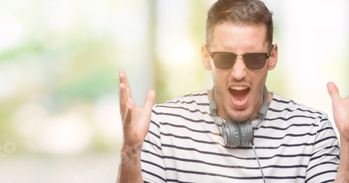 Preview: Handsome Young Man Wearing Headphones Celebrating Mad And Crazy For Success With Arms Raised And
