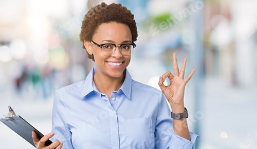 Preview: Young African American Businesss Woman Holding Clipboard Over Isolated Background Doing Ok Sign