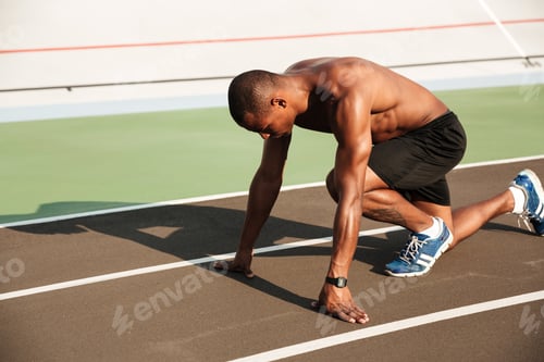 Preview: Portrait Of A Young Muscular Afro American Sportsman About To Start His Run On A Track Field