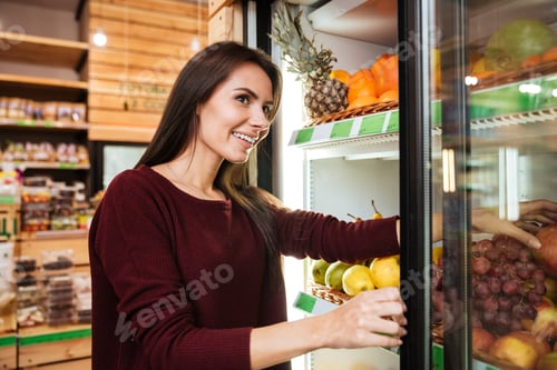 Preview: Smiling Pretty Young Woman Choosing And Buying Fruits At Grocery Shop