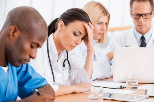 Preview: Feeling Tired And Depressed. Depressed Young Female Doctor Holding Hand In Hair While Sitting