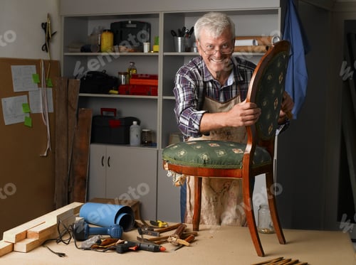 Preview: Portrait Of Retired Man Working At His Workshop. Senior Carpenter Renovating Old Chair.