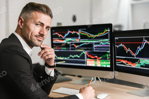 Preview: Portrait Of Confident Businessman 30S Wearing Suit Sitting In Office And Working With Digital