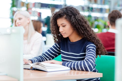 Preview: Young Afro American Woman Reading Book In Classroom With Classmates On Background
