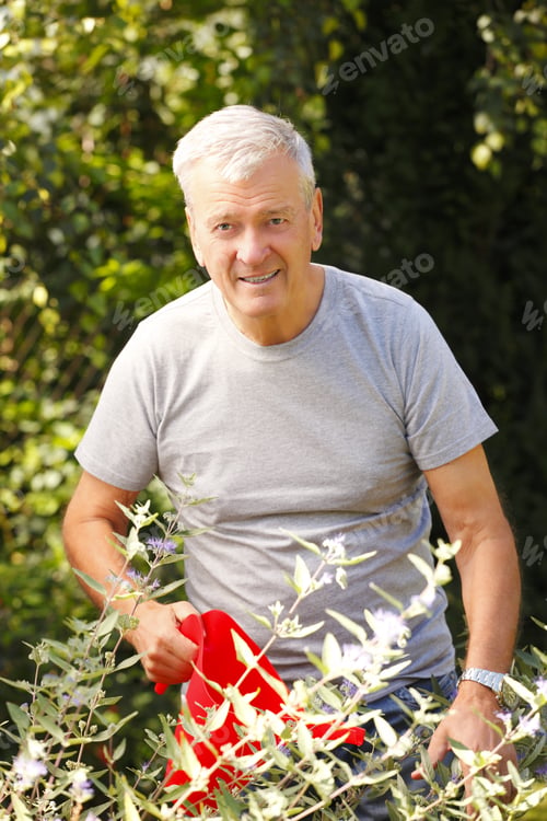 Preview: Portrait Of Retired Gardener With Can Standing At Home In Garden.