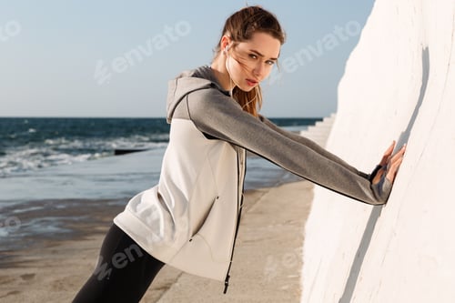 Preview: Photo Of Young Slim Sport Woman Doing Push-Ups While Standing Near White Wall, Looking At Camera