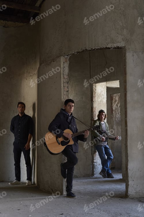 Preview: Full Length Shot Of A Young Musician With An Acoustic Guitar Leaning By The Wall While Rock Band