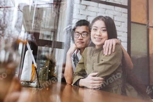 Preview: Photo Of Smiling Asian Young Loving Couple At The Cafe. Looking At Camera.