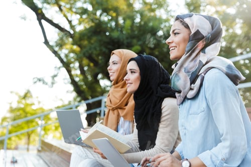 Preview: Photo Of Three Islamic Women Wearing Headscarfs Resting In Green Park And Using Laptop
