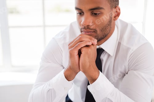 Preview: Lost In Thoughts. Thoughtful Young African Man In Shirt And Tie Holding Hands On Chin And Looking