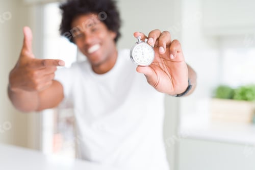 Preview: African American Man Holding Stopwatch Very Happy Pointing With Hand And Finger