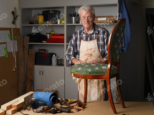 Preview: Portrait Of Retired Man Working At His Workshop. Senior Carpenter Renovating Old Chair.