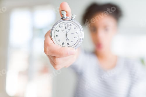Preview: Young African American Woman Holding Stopwatch Scared In Shock With A Surprise Face, Afraid And